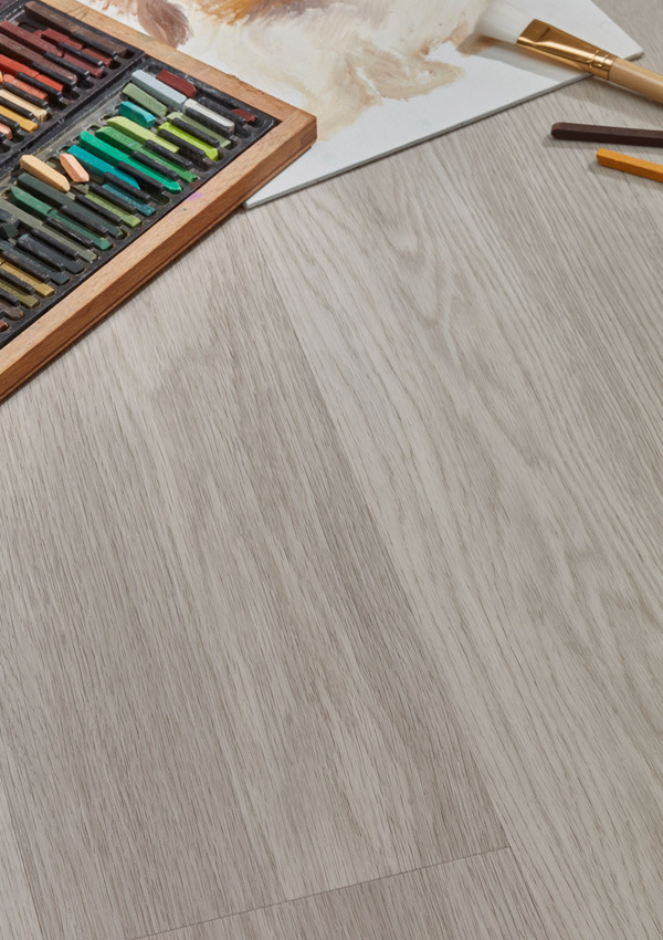 Hybrid Vinyl Flooring in colour 'Indium' with pastels, paint brush and a drawing placed on the floor.