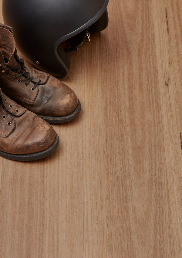 Hybrid Vinyl Flooring in colour 'Blackbutt' with brown leather boots and a black helmet placed on the floor.